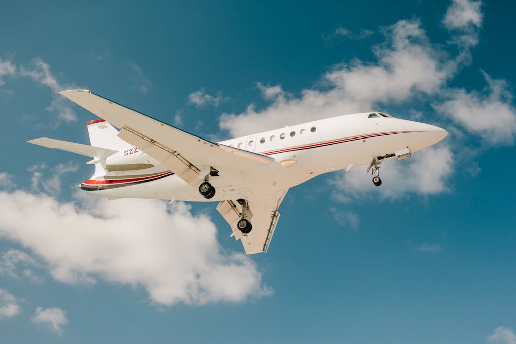 Photo by Julia Volk A sleek private jet captured mid-flight against a vibrant blue sky with scattered clouds.